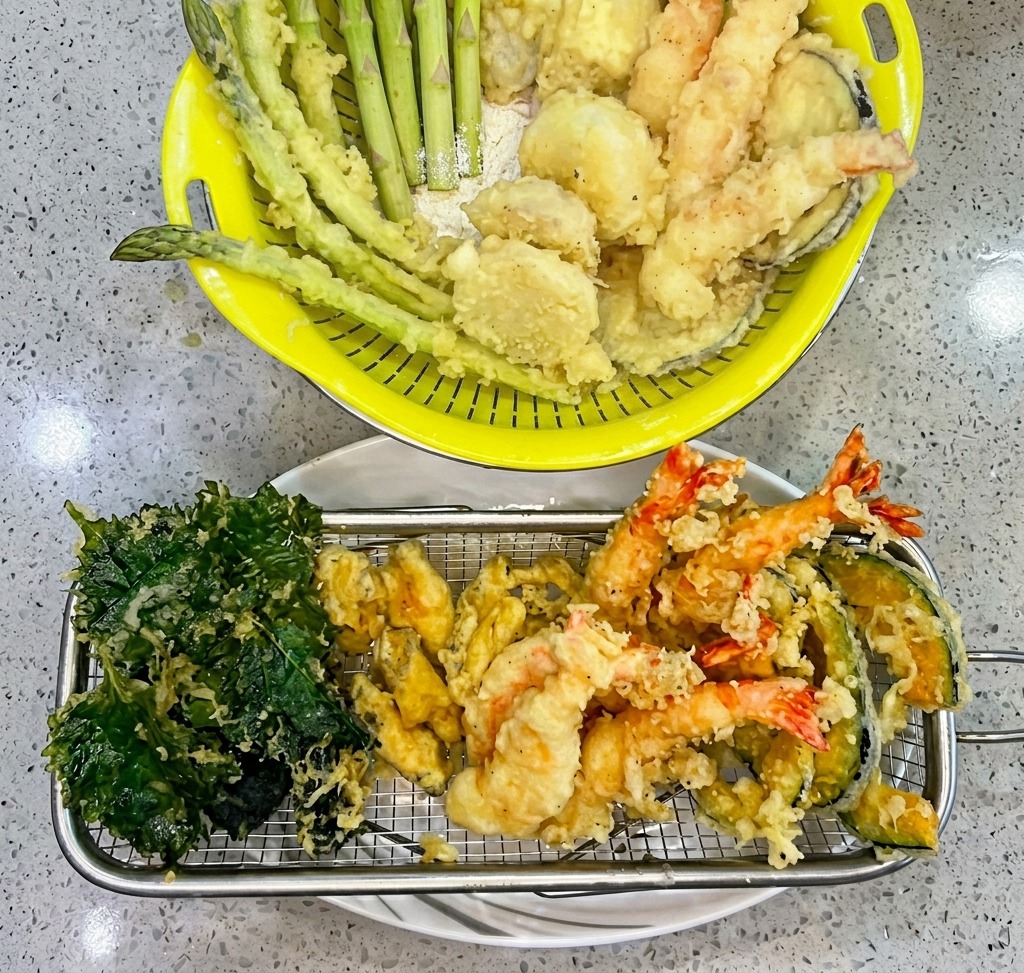 In Tempura-Teig gewendete Garnelen, die in einen Topf mit heißem Öl gelassen werden.