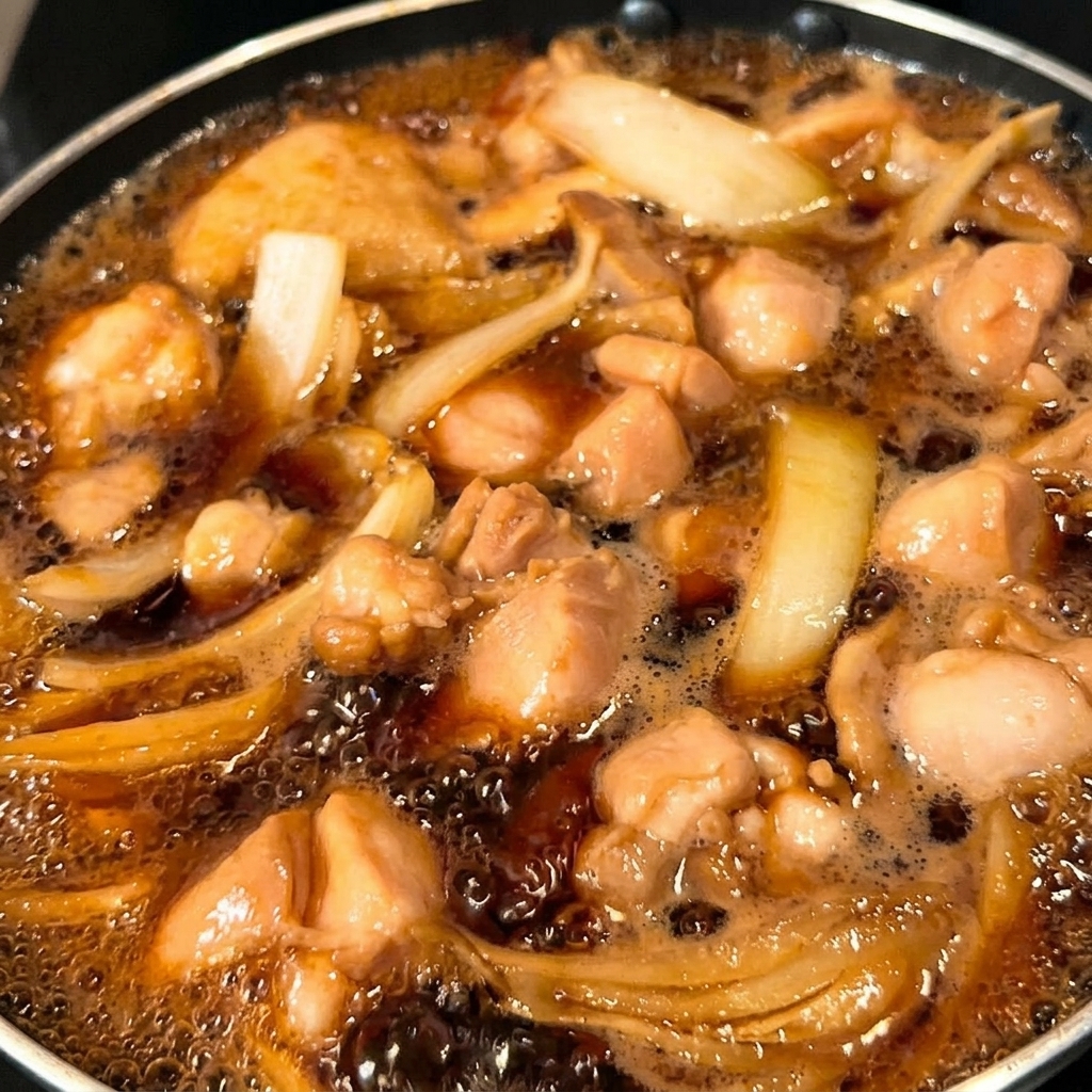 Die Hälfte der Eiermischung wird über das Hähnchen und die Zwiebeln in die Pfanne gegossen.