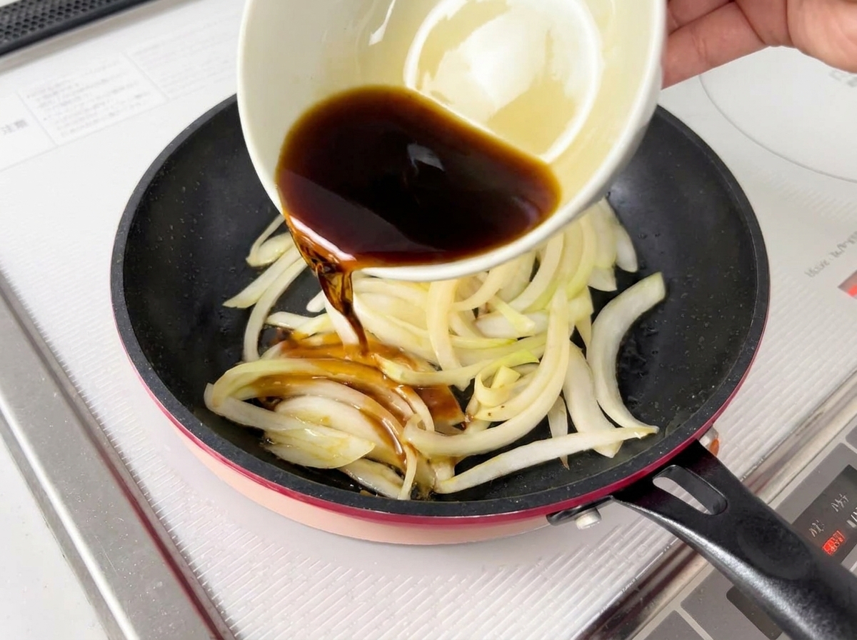 Dunkle Sauce wird aus einer weißen Schüssel über die weichen Zwiebeln in einer Pfanne gegossen.