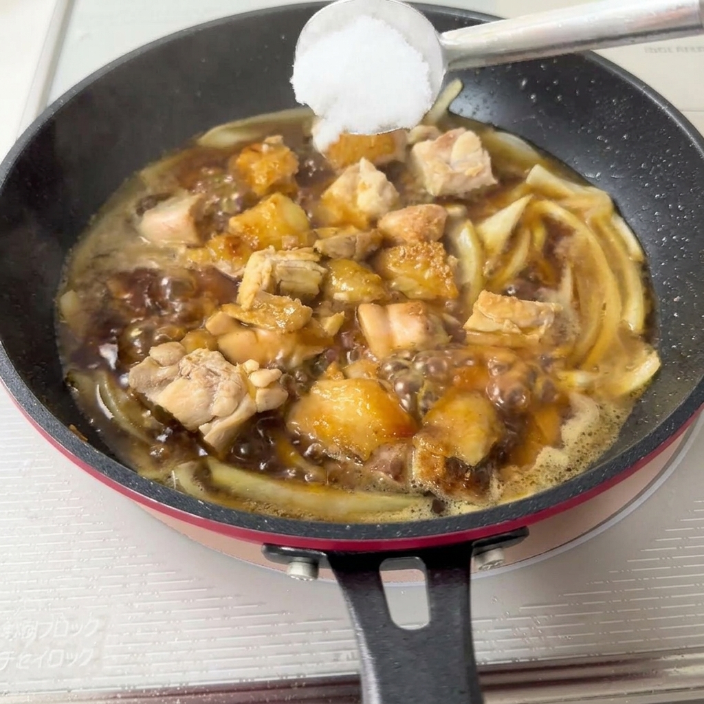 Ein Metalllöffel, der einen Berg weißen Zuckers hält, wird in die kochende Pfanne herabgelassen.