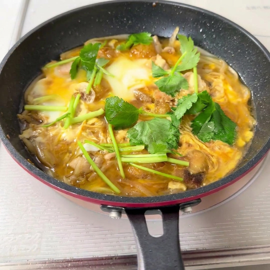 Eine Pfanne voller Oyakodon-Mischung wird über eine Schale mit weißem Reis gegossen.