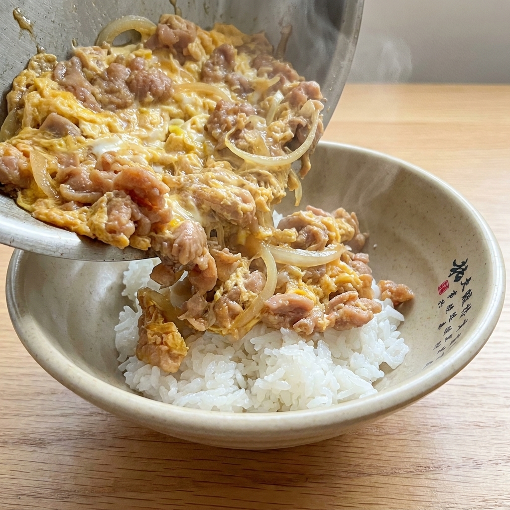 Das fertige Tanindon in einer Schale serviert, mit Schweinefleisch, Zwiebeln und cremigem Ei auf weißem Reis.