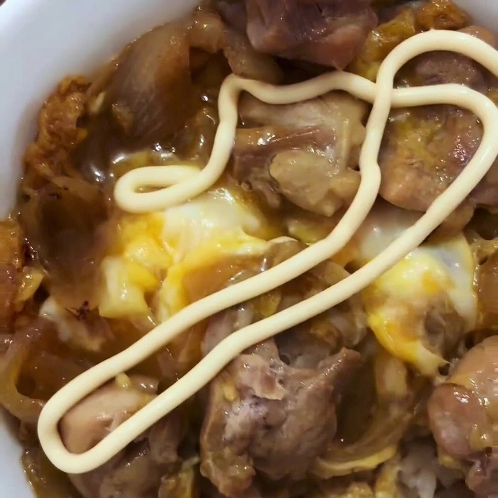 Verquirlte Eier werden über das gegarte Hähnchen und die Zwiebeln in der Pfanne gegossen.
