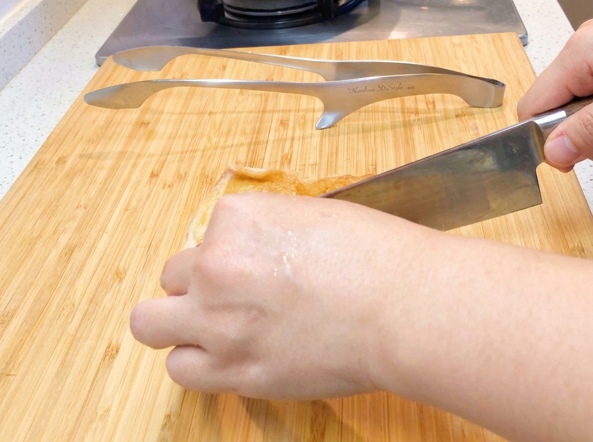 In der Pfanne gebratenes Hähnchen wird auf einem Schneidebrett in mundgerechte Stücke geschnitten.
