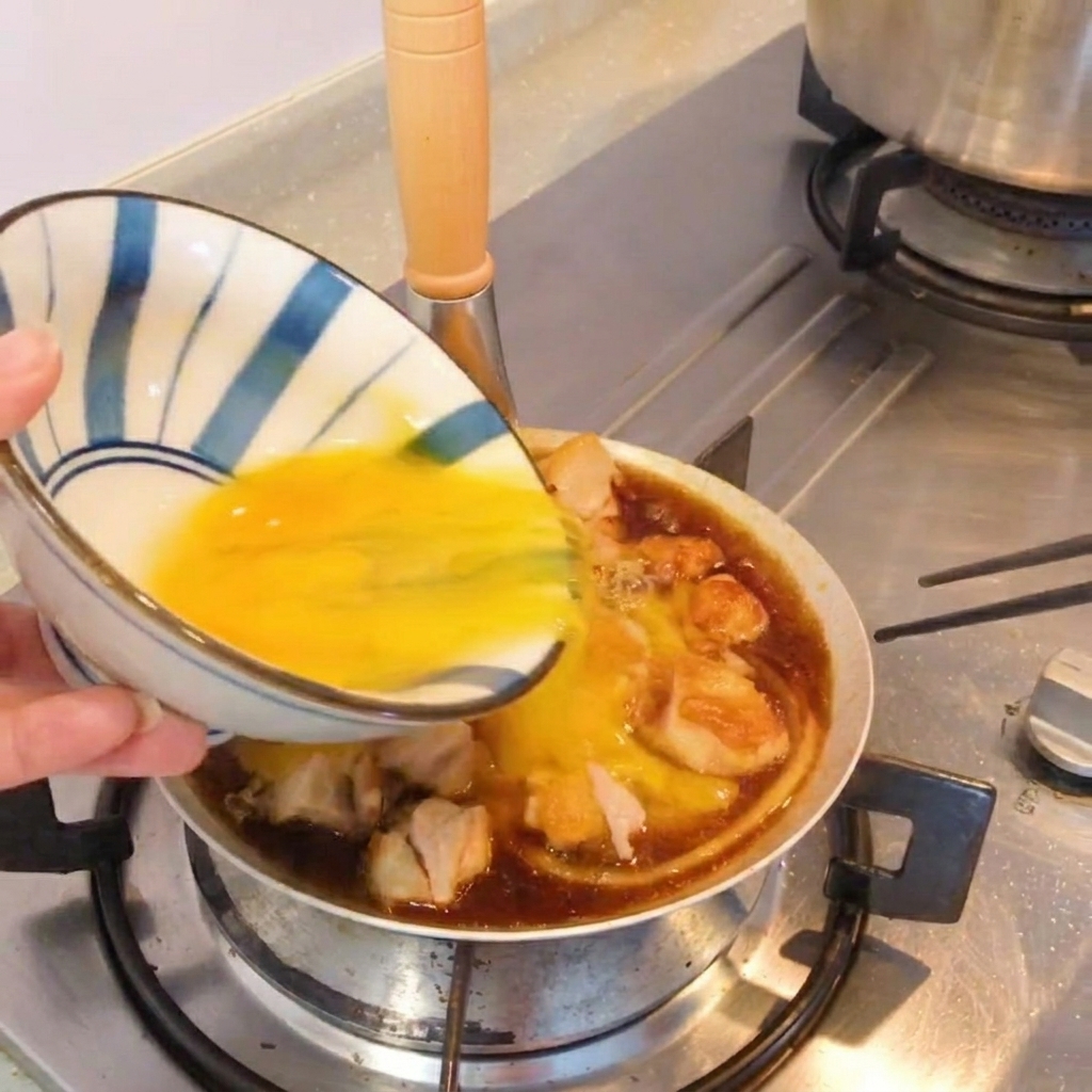 Ein fertiges Gericht im Oyakodon-Stil in einer Pfanne, garniert mit frischen Frühlingszwiebeln.
