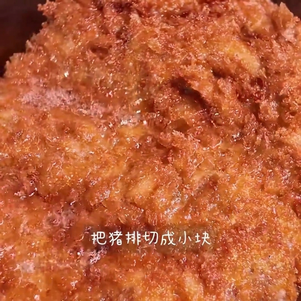 Ein knusprig goldbraunes Schweinekotelett wird auf einem Holzbrett in Streifen geschnitten.