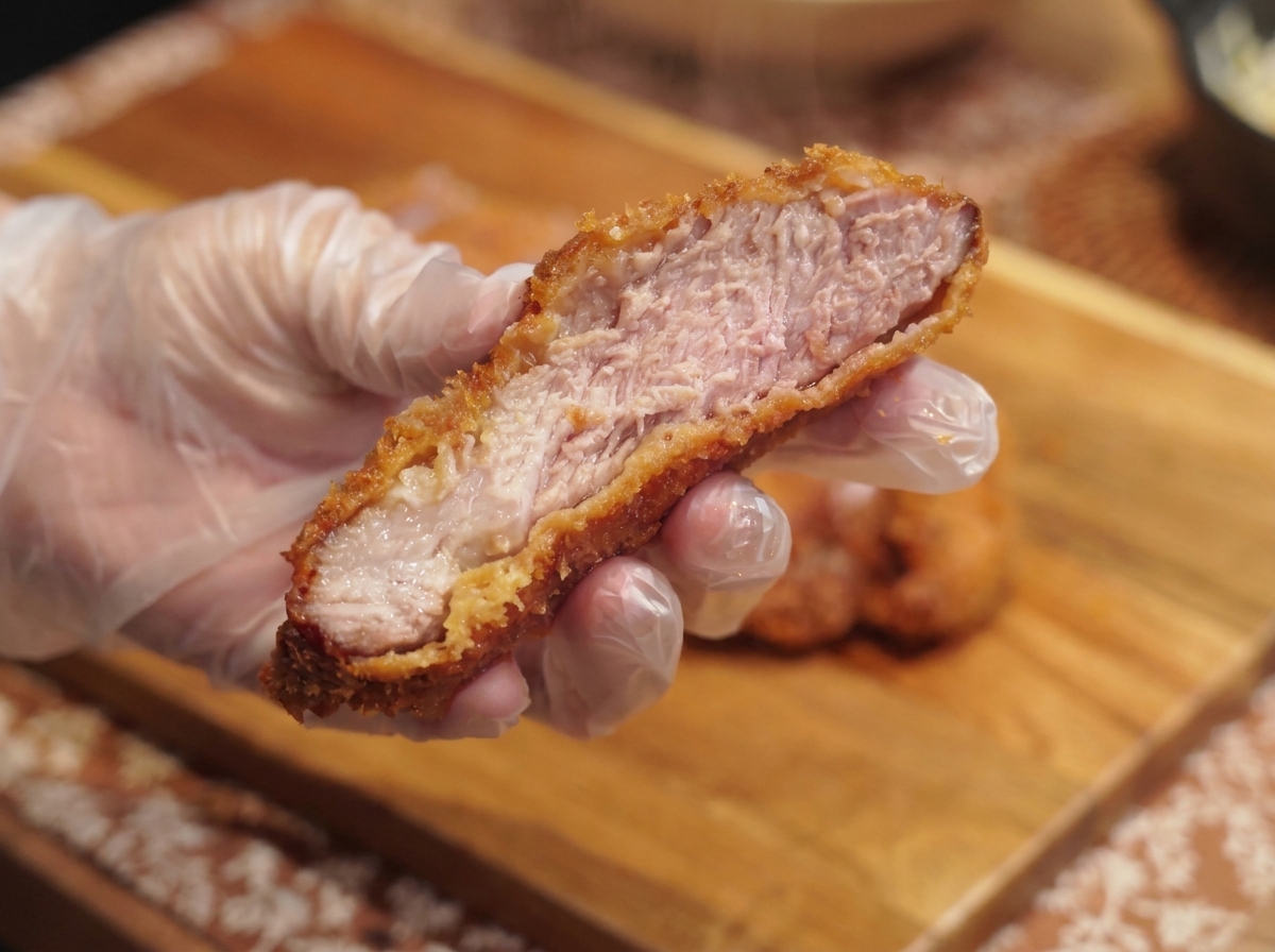 Eine fertige Schüssel mit Curryreis, weichem Ei und dem knusprigen Tonkatsu, garniert mit Petersilie.