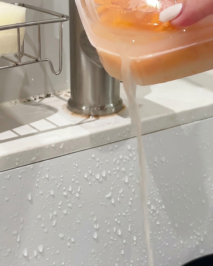 Ein Plastikbehälter mit orangefarbenem Seeigel wird über ein Waschbecken gekippt, um die Flüssigkeit abzugießen.