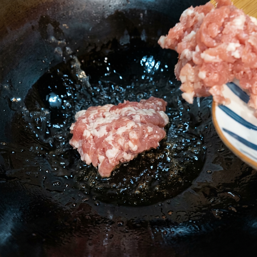 Hackfleisch wird in einem heißen Wok bei mittlerer bis niedriger Hitze angebraten, bis es gebräunt ist.