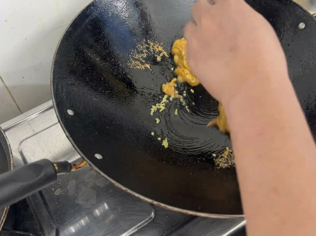 Gekochter Seeigelrogen, zerkrümelt und mit gehacktem Ingwer in einem eingebrannten Metallwok vermischt.