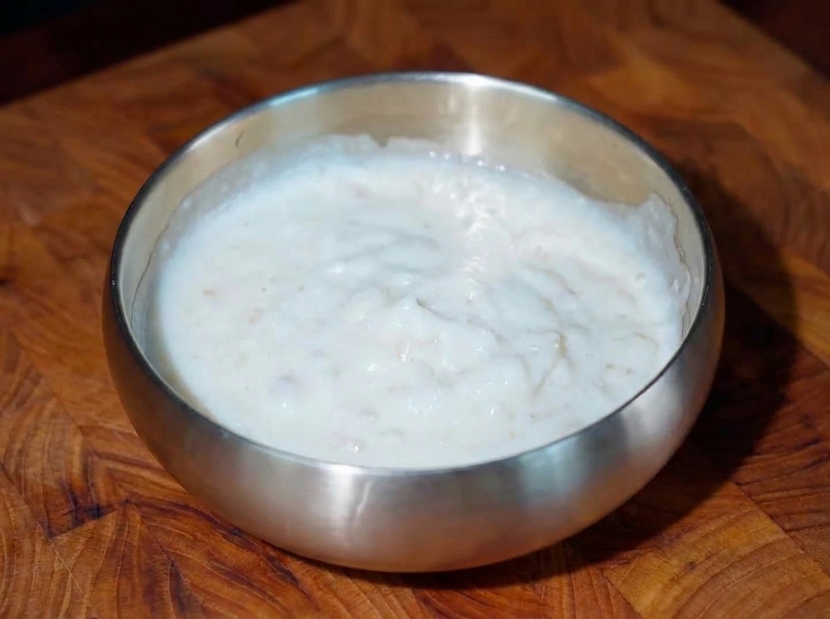 Eine Nahaufnahme von knusprig frittierten Rindfleischstücken, die mit kleinen Tupfen weißer Osmanthus-Creme garniert werden.