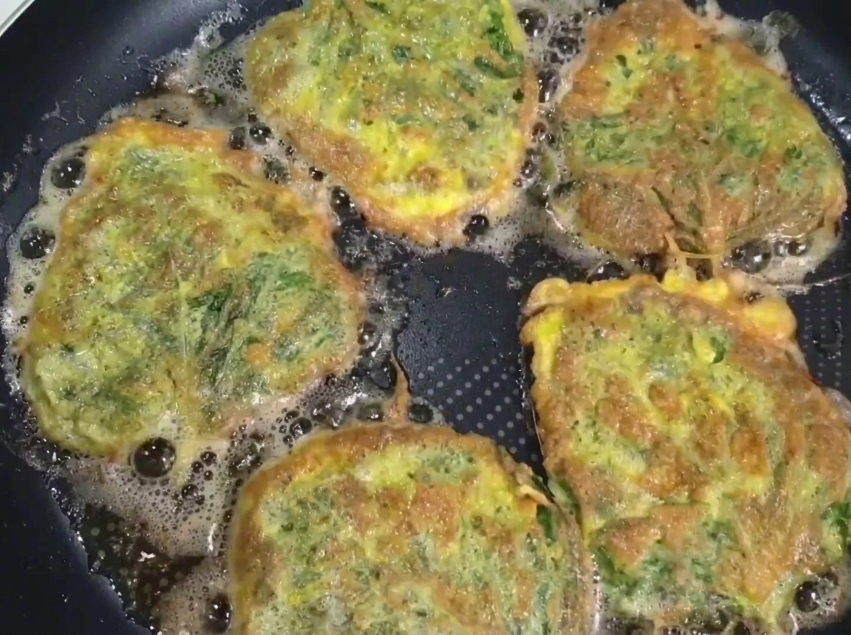 Ein gebratener Perilla-Rindfleisch-Pfannkuchen wird mit einem Pfannenwender und Stäbchen aus der Pfanne gehoben.