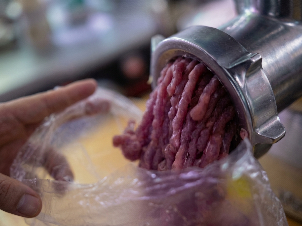 Hackfleisch, das aus einem mechanischen Fleischwolf in eine Plastiktüte gepresst wird.