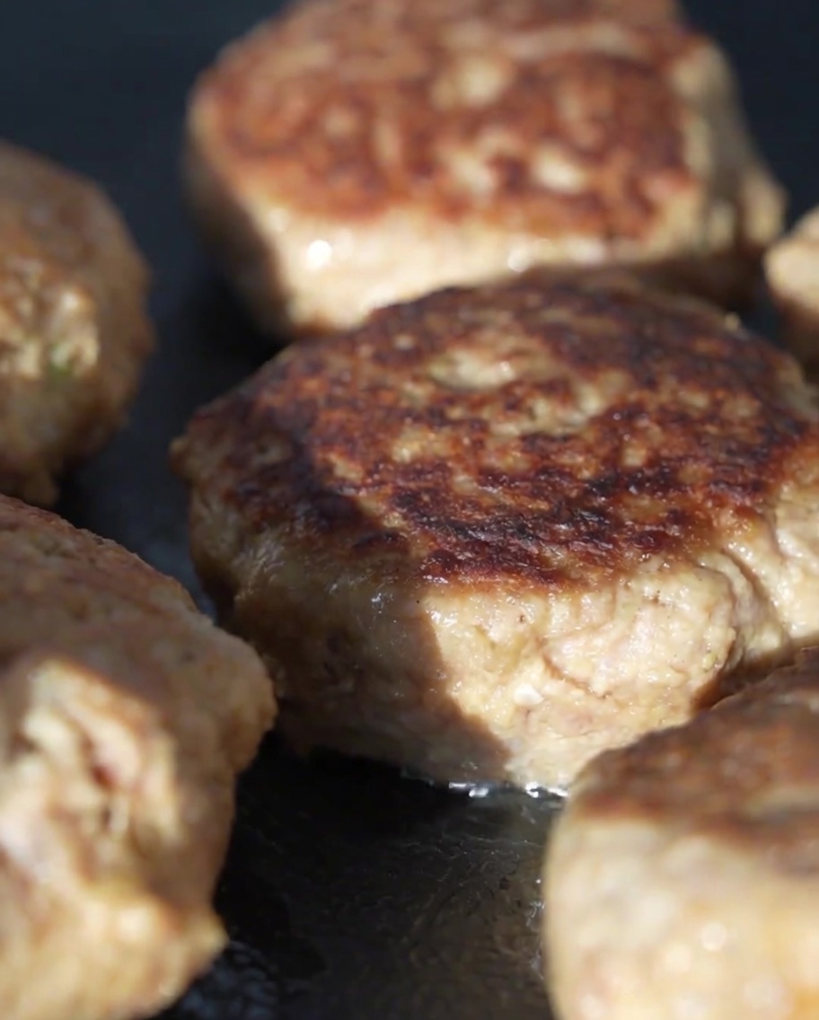 Glasdeckel, der die Pfanne mit den Fleisch-Patties abdeckt, um sie zu dämpfen.