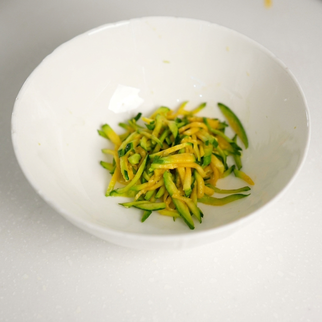 Frisches Rinderhackfleisch wird in die Schüssel mit den abgetropften Zucchinistreifen gegeben.