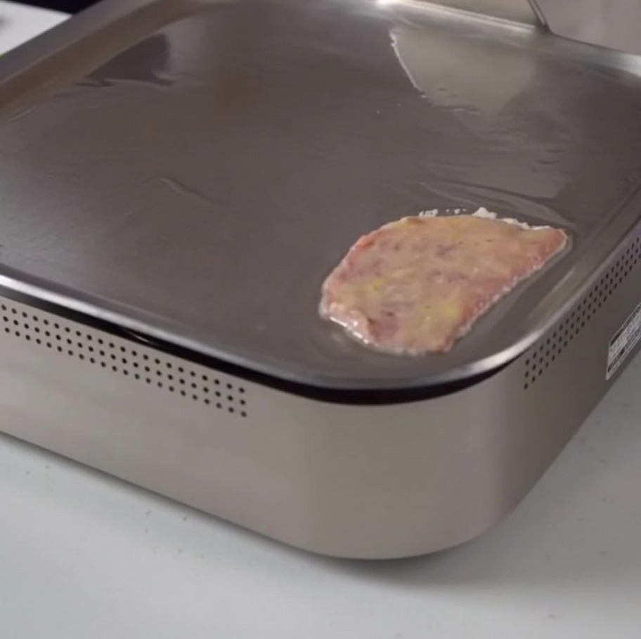 Ein mit Ei überzogenes Stück Rindfleisch brät sanft auf einer glatten Grillplatte.