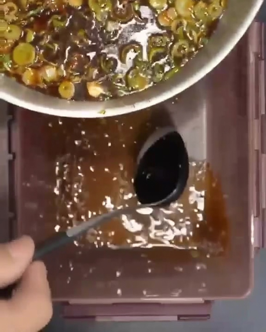 Rohe Rippchen werden schichtweise in einen Behälter gelegt und mit der würzigen Marinade übergossen.
