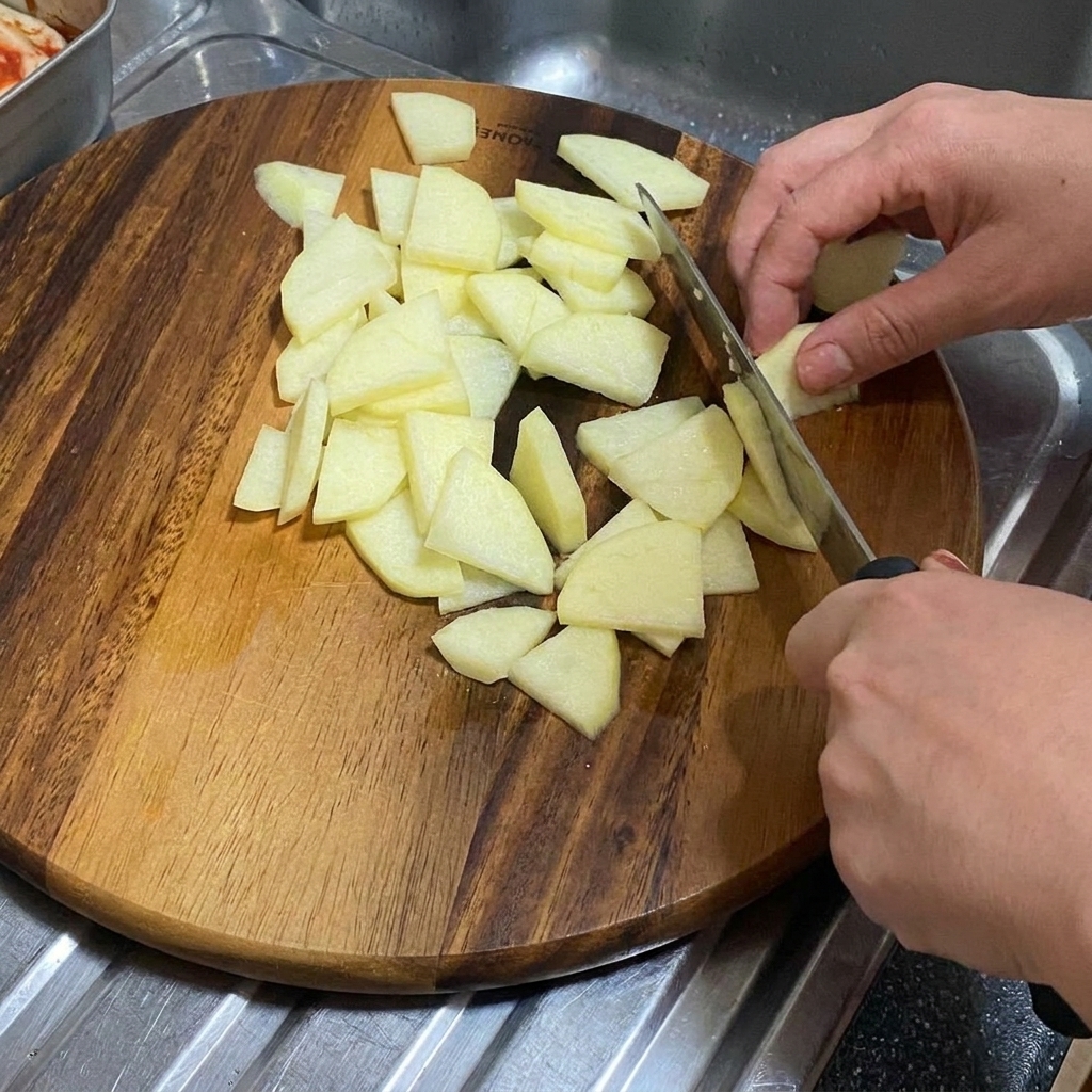 Eine Zwiebel wird in dicke Spalten auf einem Holzschneidebrett geschnitten.