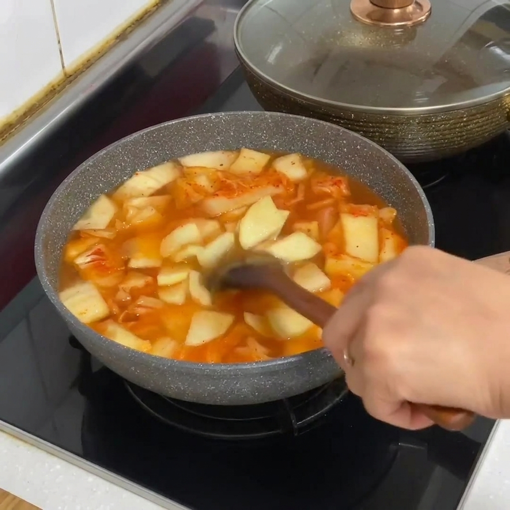 Glasnudeln werden in den Topf mit kochendem Kimchi-Eintopf gegeben.