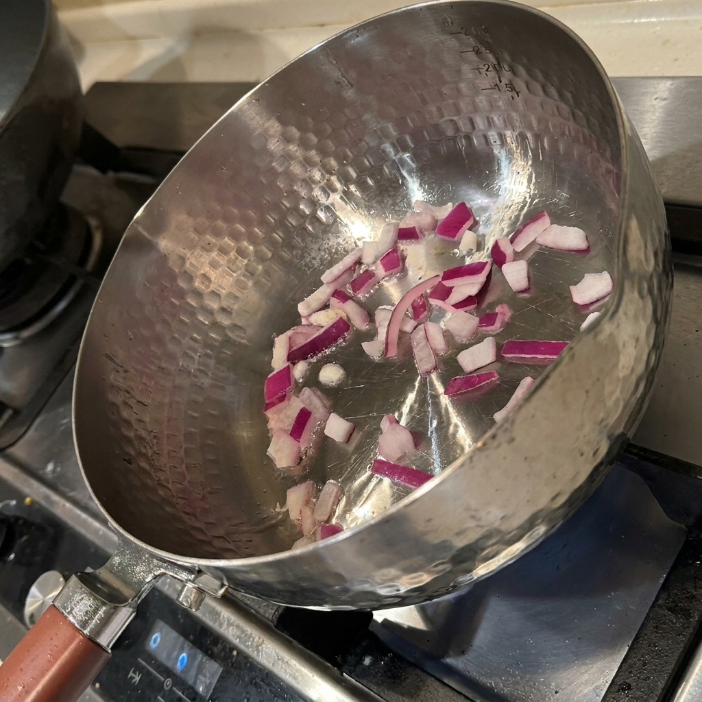 Zwiebelwürfel braten in einer heißen Pfanne mit Öl und werden glasig und duftend.