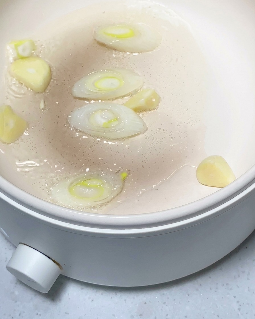 Kartoffelstücke, gehackter Knoblauch und Ingwer werden in einer leicht geölten Pfanne angebraten.