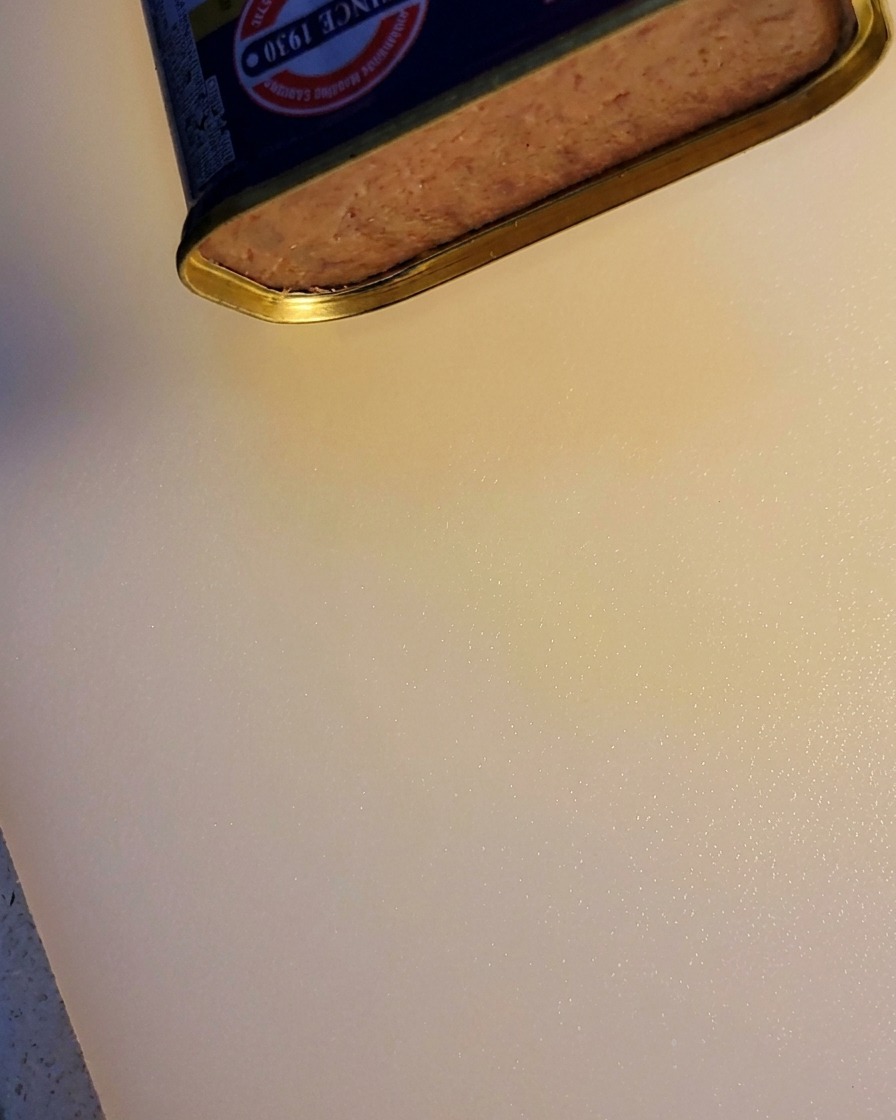 Ein Block Frühstücksfleisch wird aus der Dose geschnitten.