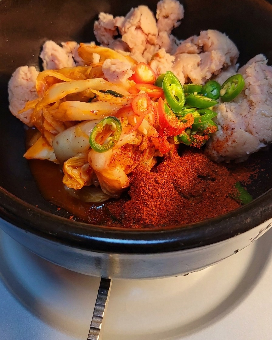 Nahaufnahme von Zucker und Rinder-Gewürzpulver, die über Kimchi und Fleisch gestreut werden.