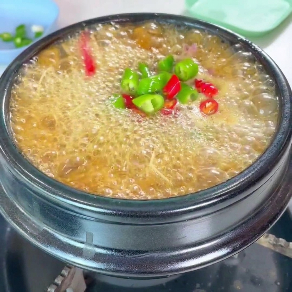 Gehackte grüne und rote Chilischoten sowie Frühlingszwiebeln werden als Topping auf den Eintopf gestreut.