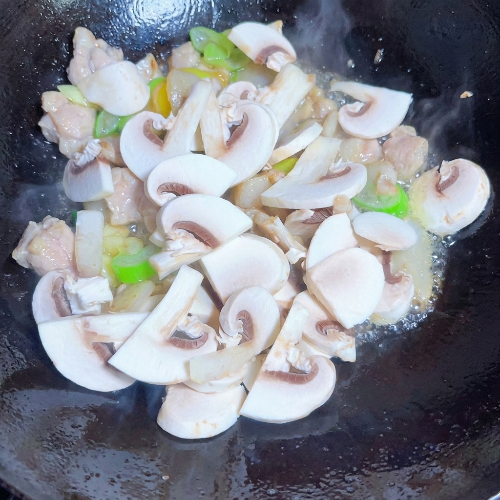 Eine Mischung aus Pilzen, Zwiebeln und Sojasprossen wird mit Gewürzen in der Pfanne geschwenkt.