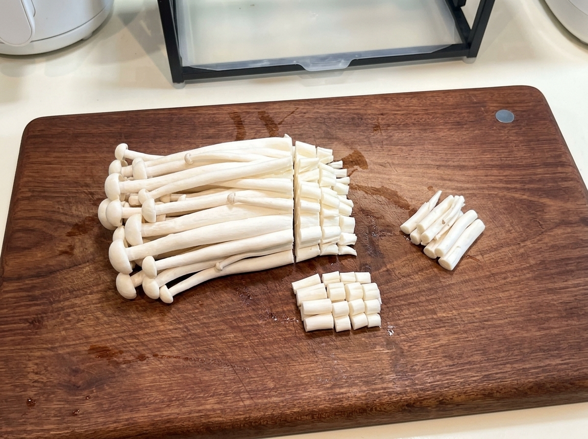 Frische Meeresfrüchte-Pilze auf einem Holzbrett, deren holzige Enden mit einem Messer abgeschnitten werden.