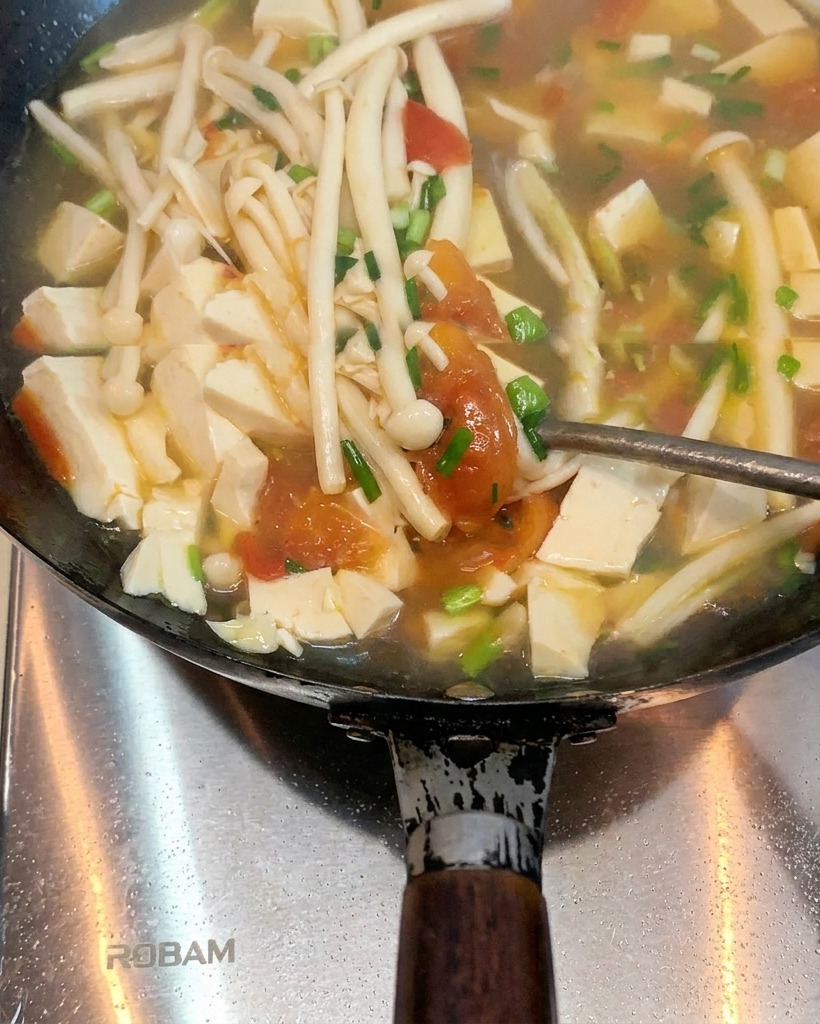 Tomaten braten in einem Wok mit geschmolzenem Schmalz und beginnen, weich zu werden und Saft abzugeben.