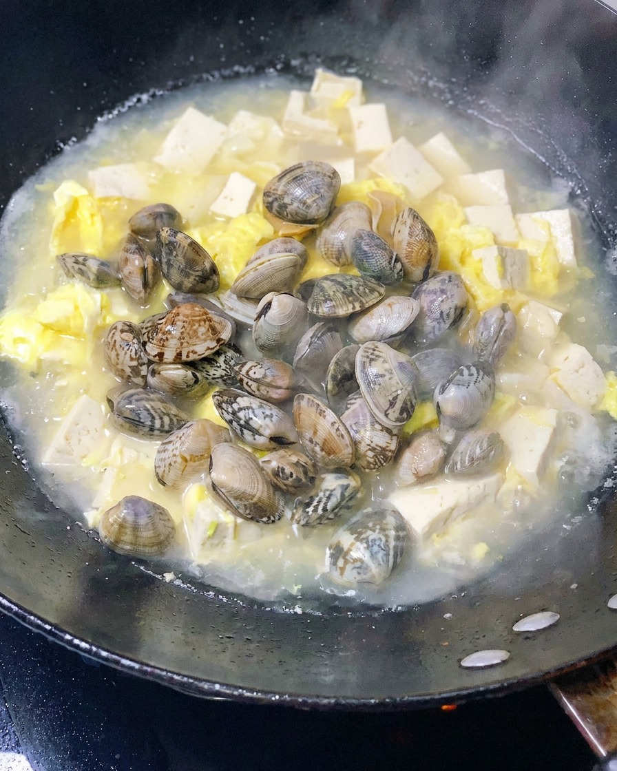 Frische Muscheln werden in den Topf mit Tofu und Eiern gegeben.