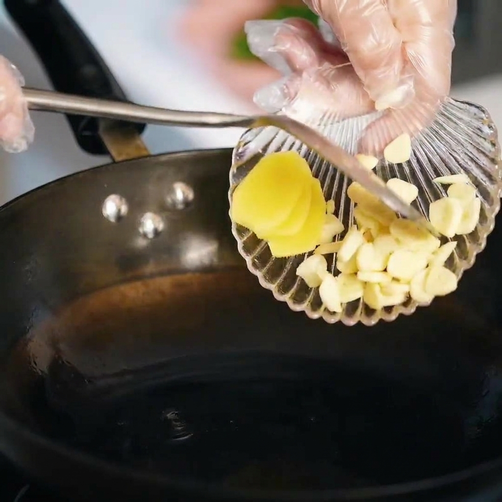 Knoblauch- und Ingwerscheiben werden in geschmolzenem Schmalz angebraten.