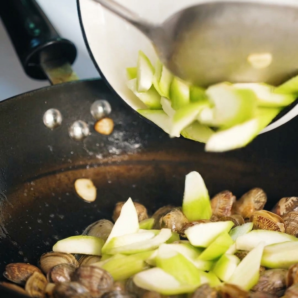 Luffascheiben werden zusammen mit den Muscheln in der Pfanne angebraten.