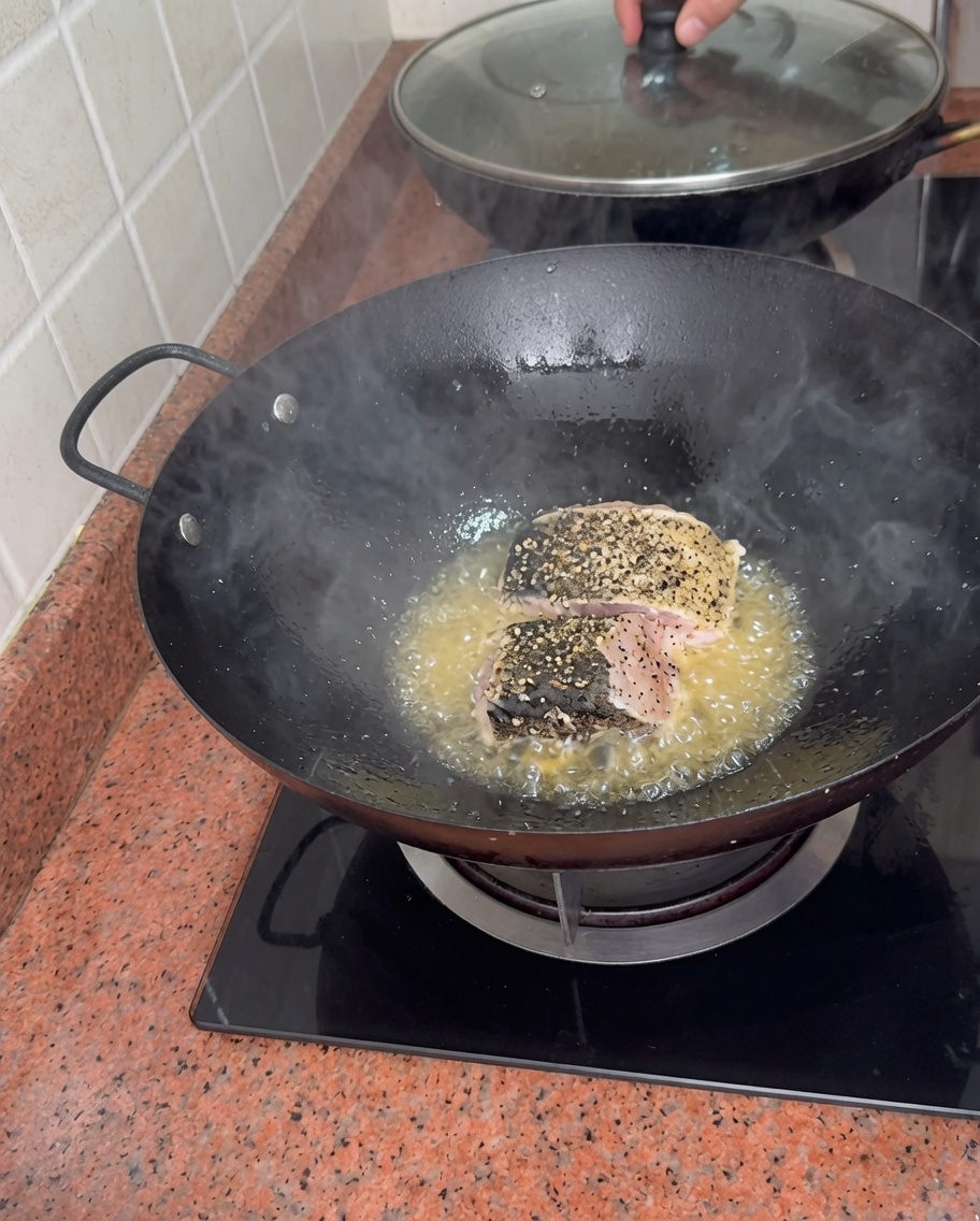 Dickere Stücke gewürzter Zackenbarsch braten in sprudelndem Öl im Wok.