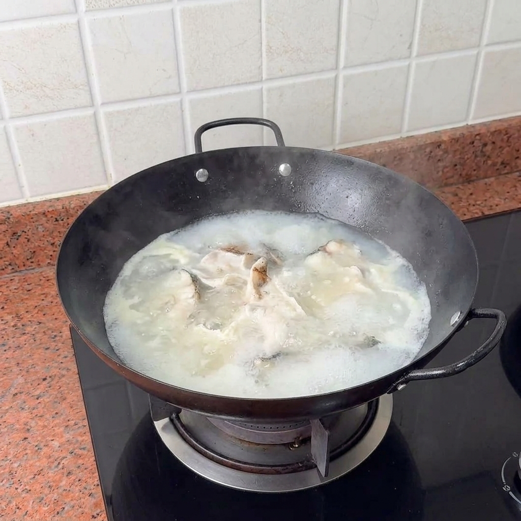 Tofuwürfel werden vorsichtig in die kochende, cremige Fischsuppe gegeben.