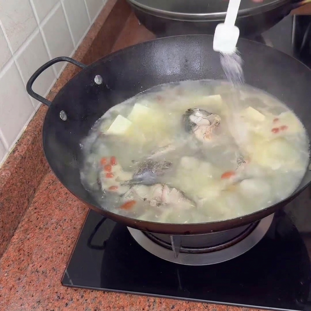 Gewürze werden in die Suppe gegeben, während sie mit Tofu und Goji-Beeren köchelt.