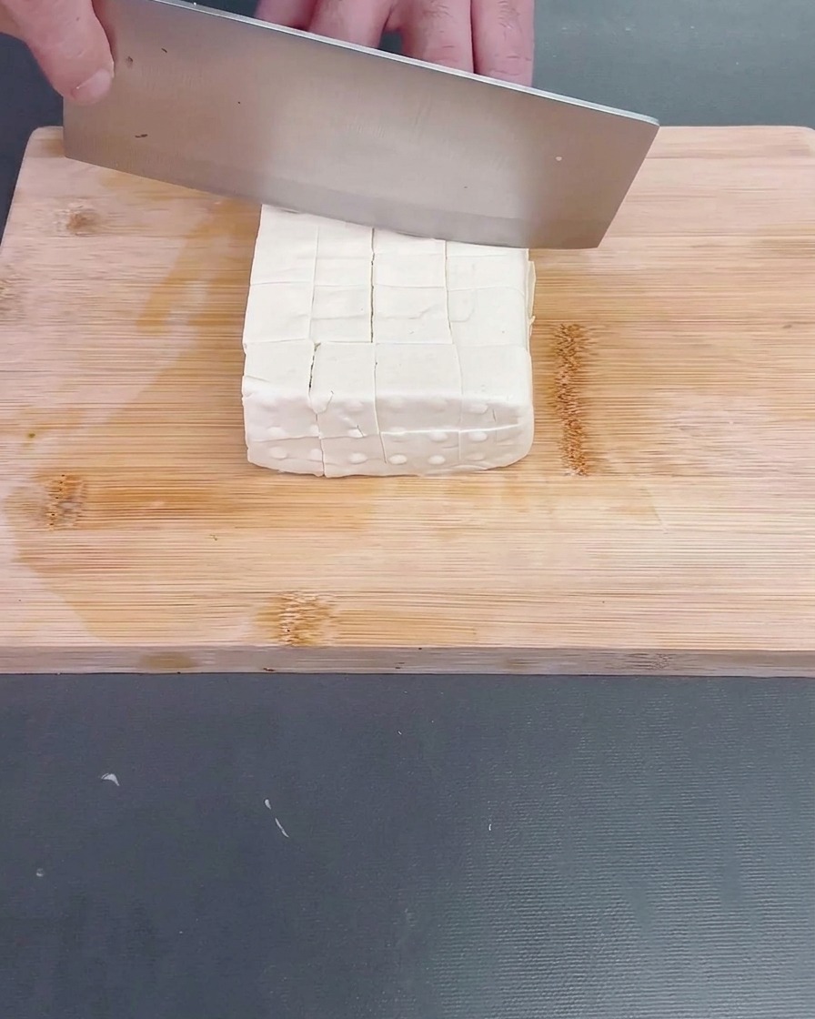 Eine frisch geschälte Luffa wird in unregelmäßige, mundgerechte Stücke geschnitten.