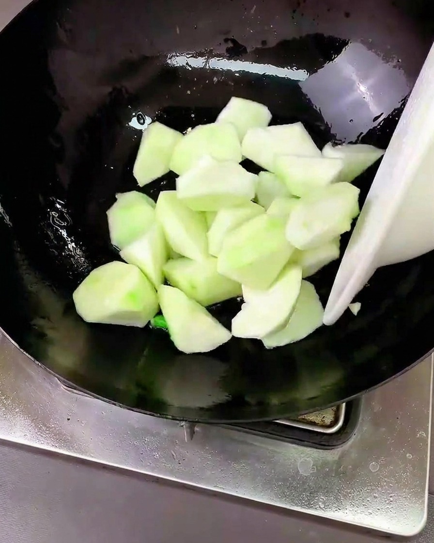 Luffa-Stücke werden im Wok mit den Aromaten verrührt.