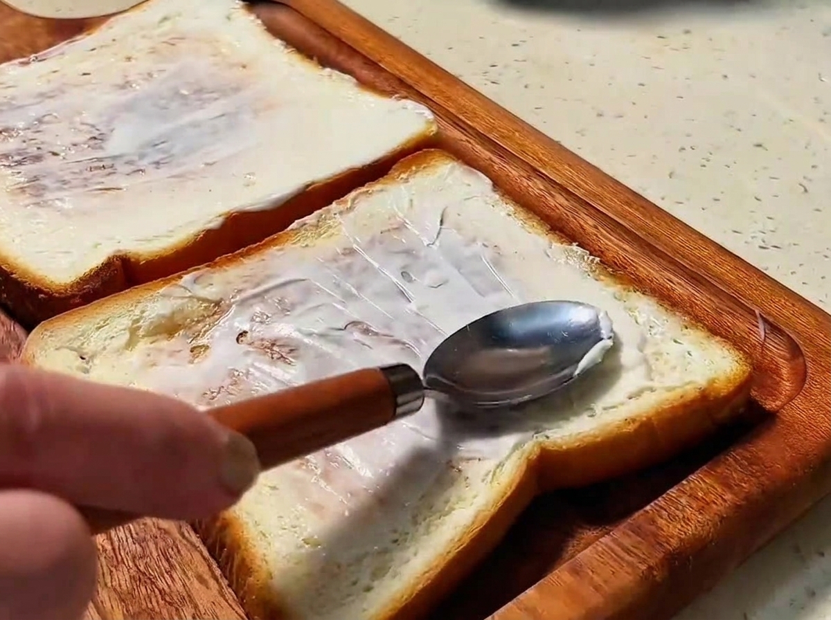 Zwei goldbraune Brotscheiben, die mit einer Schicht Mayonnaise bestrichen sind.