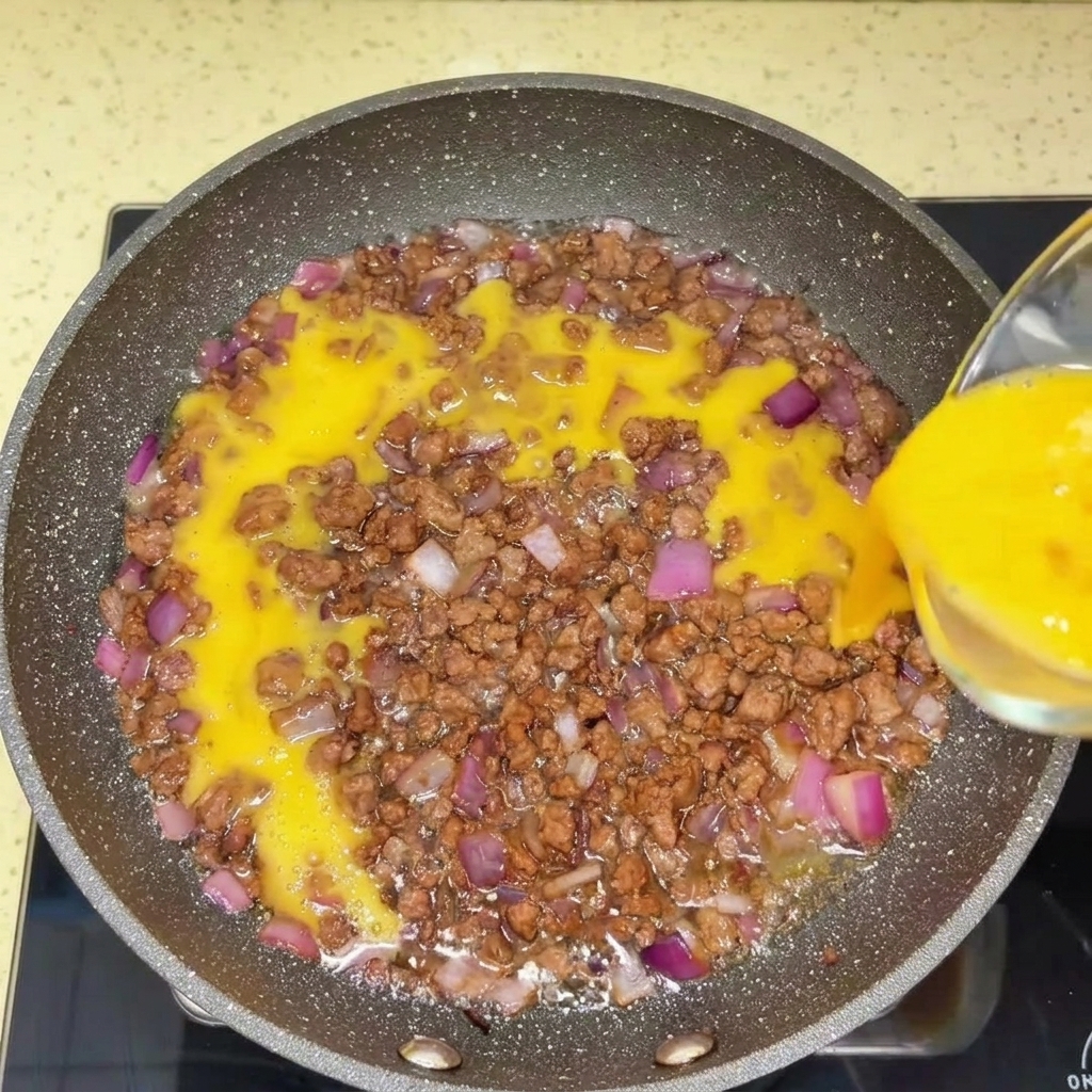 Rinderhackfleisch wird mit einem Pfannenwender in einer heißen Pfanne zerkleinert.