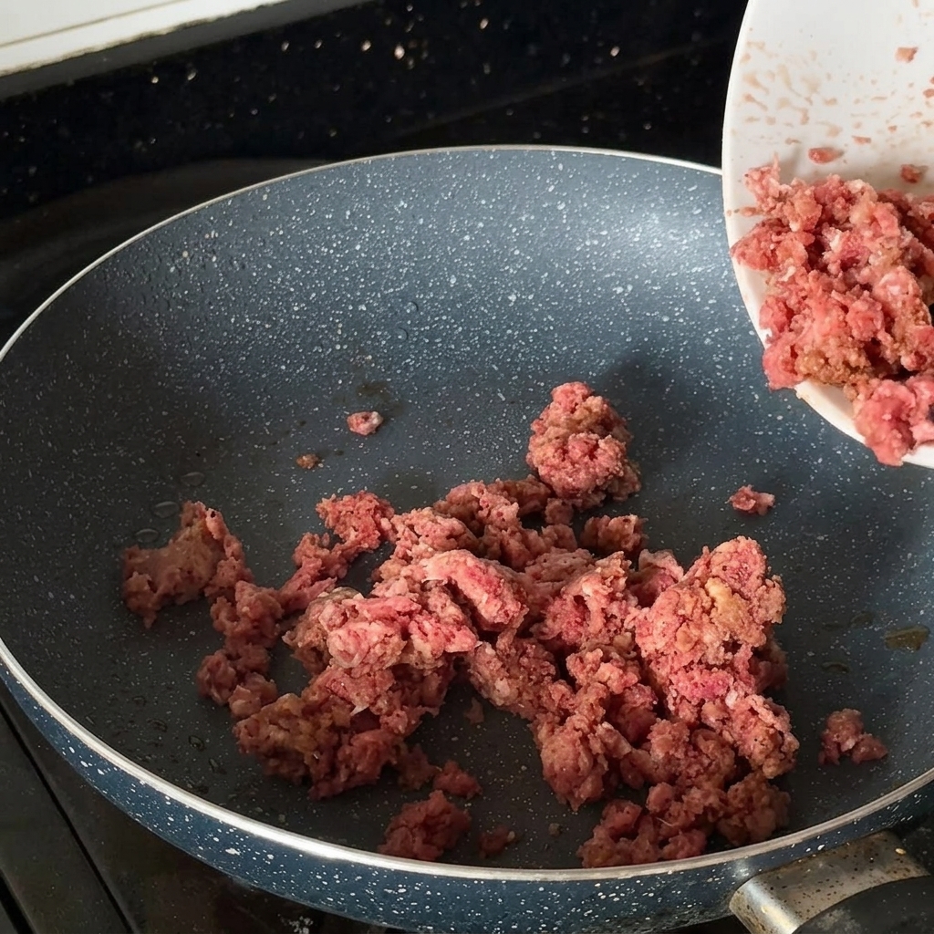 Gewürztes Hackfleisch bräunt in einer heißen Pfanne.