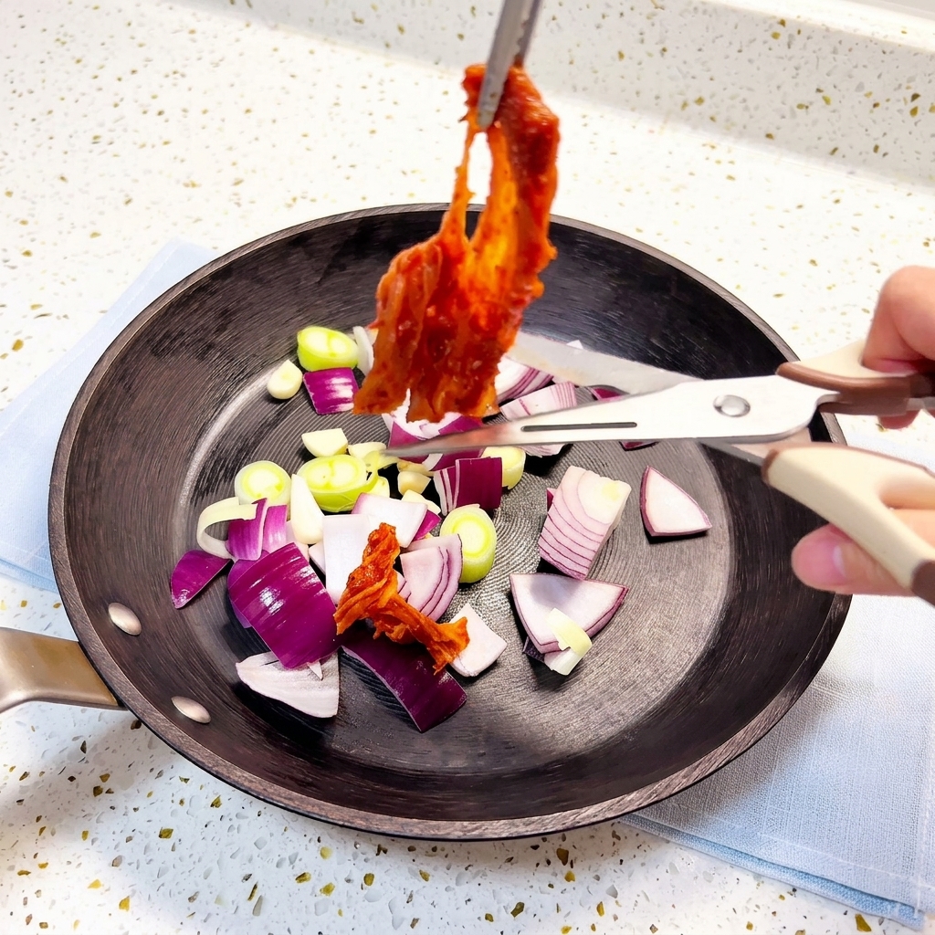 Kimchi wird mit einer Küchenschere direkt in die Pfanne geschnitten.
