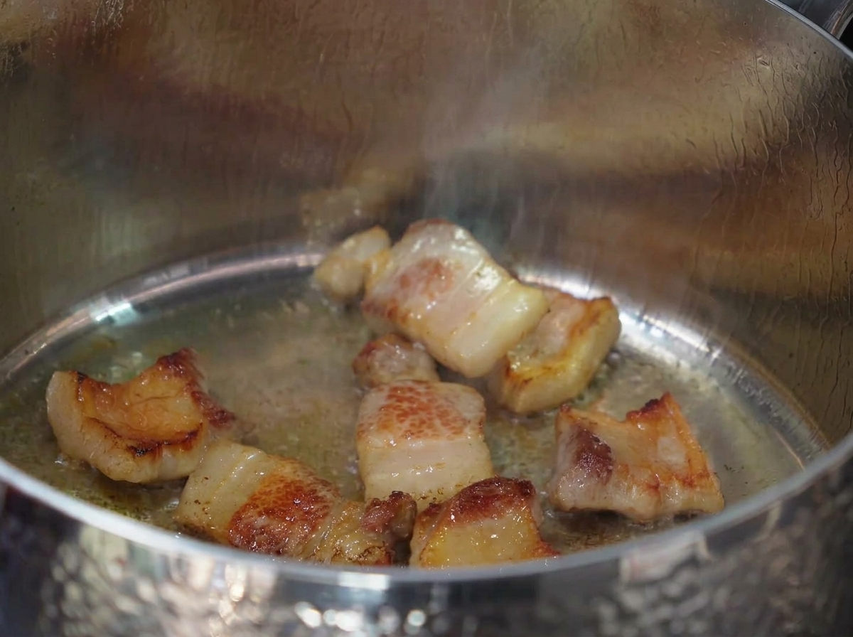 Gehackter Knoblauch wird in das ausgelassene Schweinefett und Fleisch gerührt.