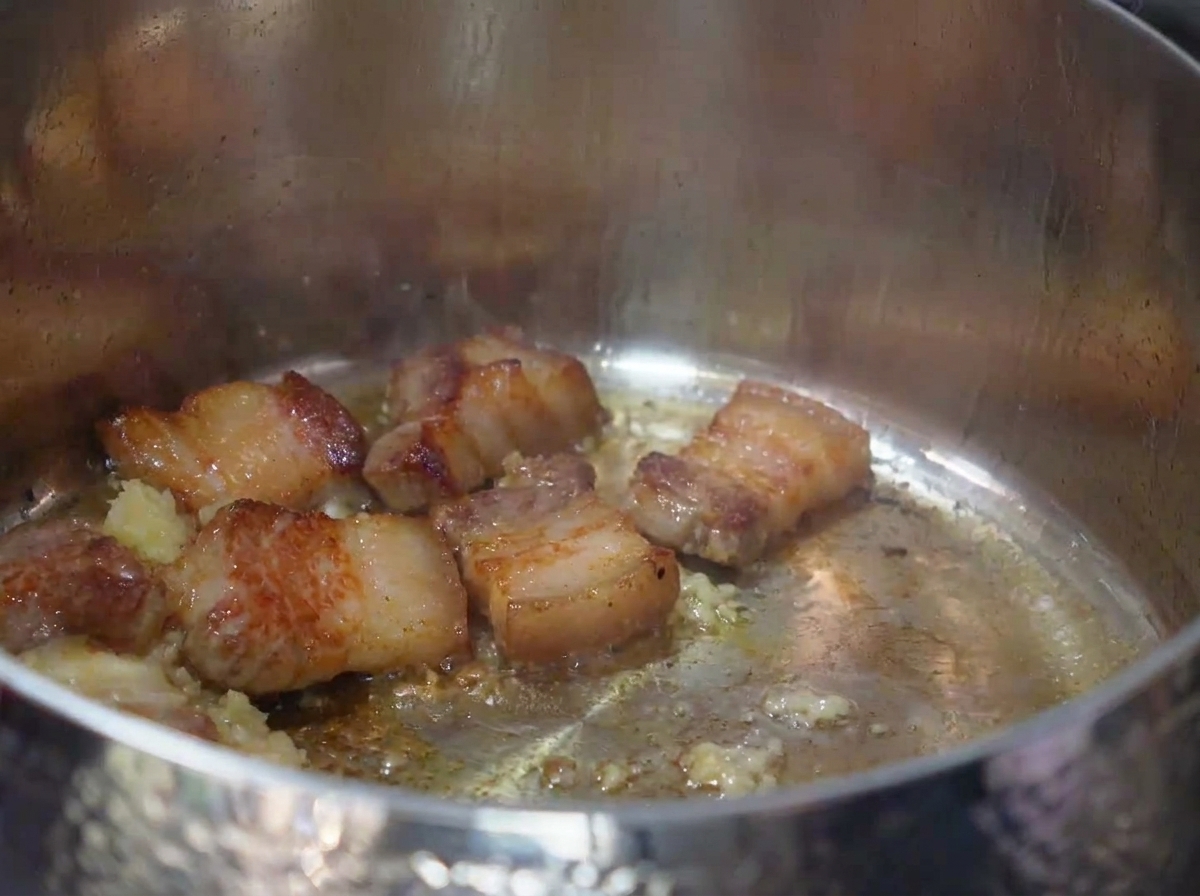 Gehacktes Kimchi wird in den Topf zum angebratenen Schweinefleisch und Knoblauch gerührt.
