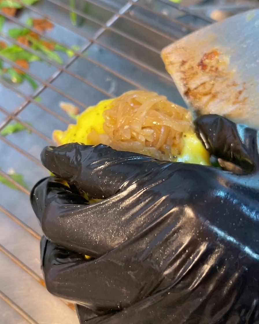 Ein Burger-Patty wird auf den Basisturm gelegt, garniert mit würziger Fleischsauce und frischen grünen Jalapeño-Scheiben.