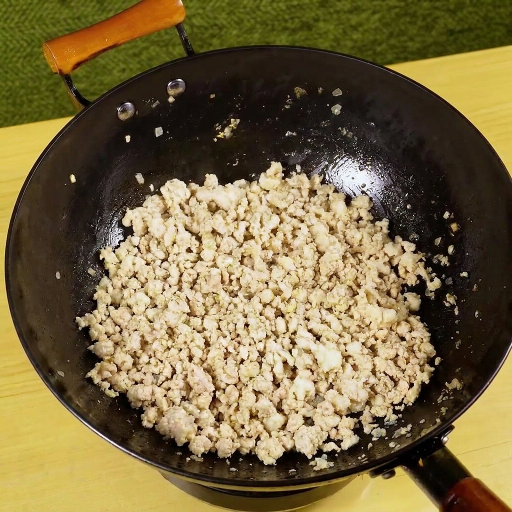 Gehackte grüne Chilischote wird in die Pfanne zum angebratenen Hackfleisch gegeben.