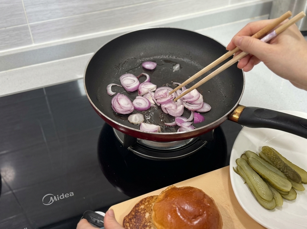 Rote Zwiebelstreifen werden mit Stäbchen in einer heißen Pfanne angebraten.