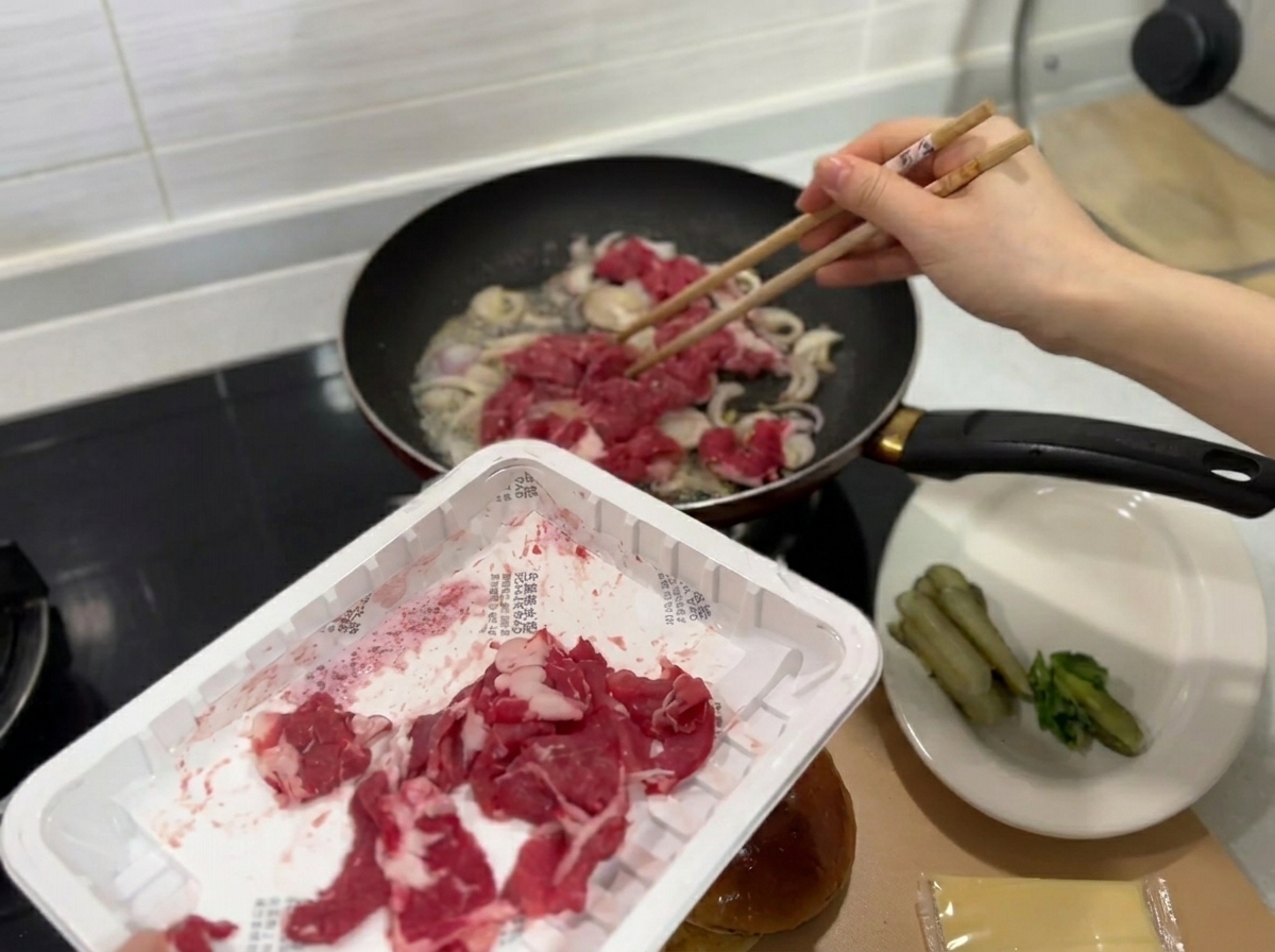 Dünne Rindfleischstreifen werden zu den Zwiebeln in die Pfanne gegeben.