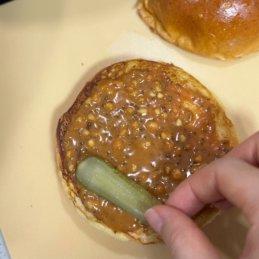Eingelegte Gurkenscheiben werden auf der Sauce platziert.